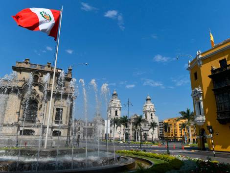 Main Town Square or Plaza Mayor or Plaza de Armas of Lima in the Historic Center of Lima. Surrounded by the Cathedral of Lima (in front) and Presidential Palace, to the left. Peru national flag above the fountain. Hard to believe, but there were almost no people in a middle of the day, at the usually crowded main square. It happened, because Presidential Palace Guard expected an incoming crowd of protesters and closed the square. It was a delight for photographers.